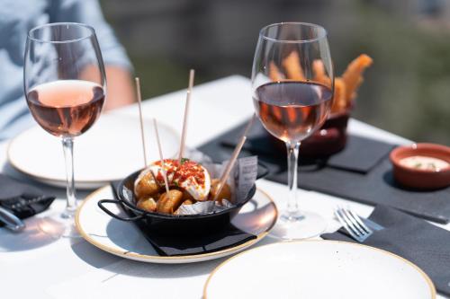 a table with two glasses of wine and a bowl of food at Gran Hotel Havana 4Sup by Escampa Hotels in Barcelona