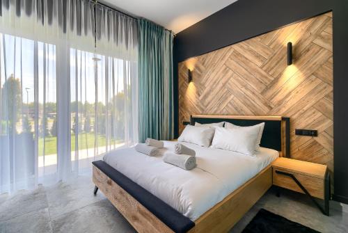 1 dormitorio con 1 cama grande y pared de madera en Apartamenty Laguna Beskidów - A54, en Zarzecze