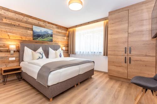 a bedroom with a large bed and a chair at Kaiser Apart Walchsee - Familie Hall in Walchsee