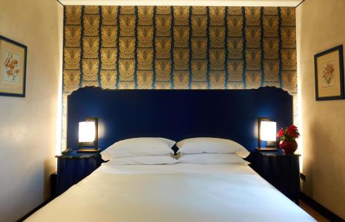 a bedroom with a large bed with a blue headboard at Hotel Verdi Boutique Hotel in Parma