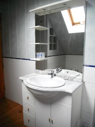 une salle de bain blanche avec un lavabo et un miroir dans l'établissement Le grand large 1, à Coulogne