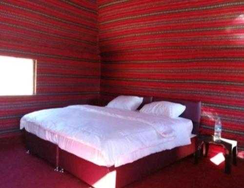 a bed in a room with a red wall at saleem with jeep tour in Wadi Rum