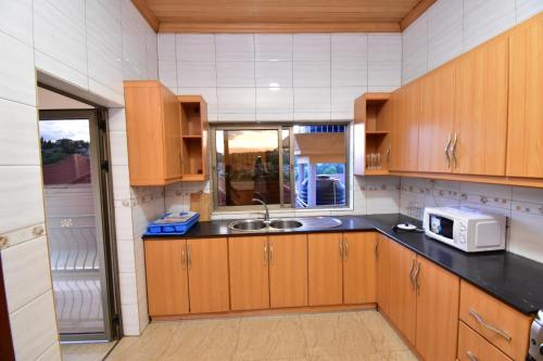 a kitchen with wooden cabinets and a sink and a microwave at Kigali Nice Apartment in Kigali
