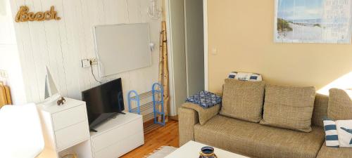 a living room with a couch and a tv at Bungalow Koje in Kröslin