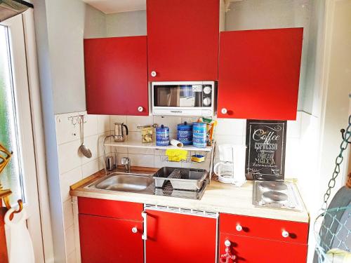 a small kitchen with red cabinets and a sink at Bungalow Koje in Kröslin