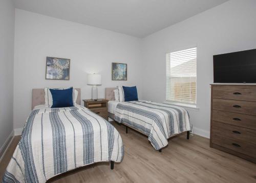 a bedroom with two beds and a flat screen tv at Sweet Escapes House in Foley