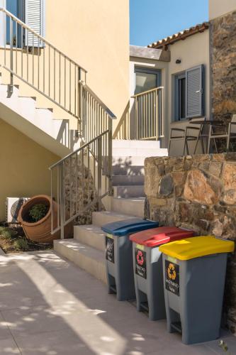 three trash cans sitting on a sidewalk next to stairs at Evge Experience Boutique Hotel in Kafoúros