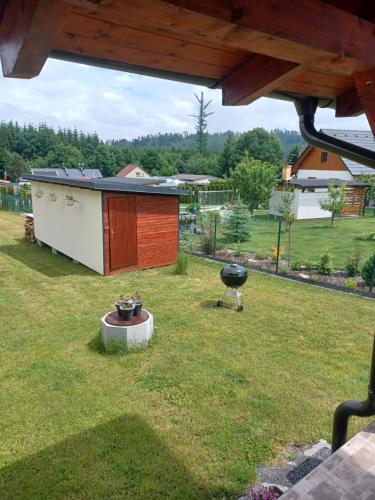 a barbecue grill in a yard with a house at Chalupa Na blátě in Hoješín
