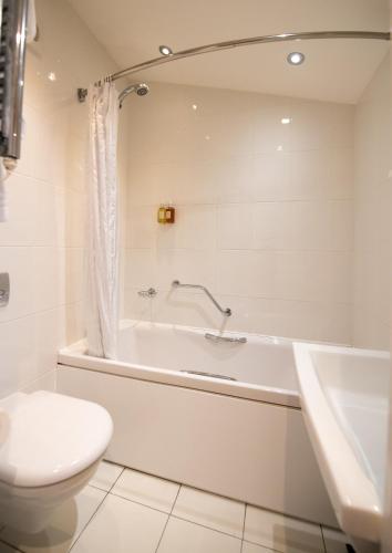 a bathroom with a tub and a toilet and a sink at The Devon Hotel in Exeter