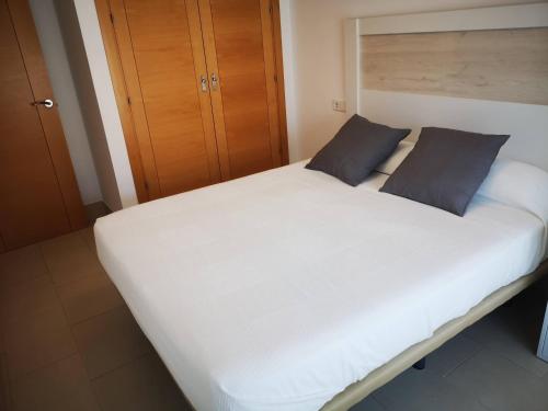 1 cama blanca grande con 2 almohadas azules. en Camposoto, en San Fernando