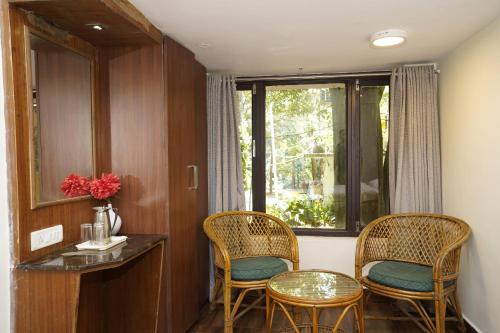 a room with two chairs and a table and a window at Zeenath Taj Gardens in Yelagiri