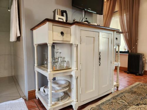a white cabinet with dishes on it in a room at Villa Tarentaal in Tulbagh