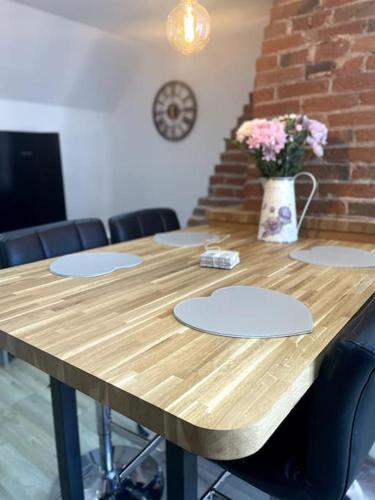 a wooden table with chairs and a vase of flowers at Cosy apartment in Eccleshall in Eccleshall
