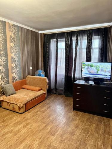 a living room with a couch and a flat screen tv at Апартаменты в самом Центре прПобеды 90 in Chernihiv