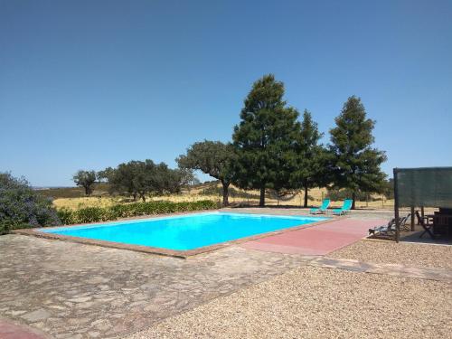 una piscina con 2 tumbonas y árboles en Herdade do Monte Outeiro - Turismo Rural, en Venda