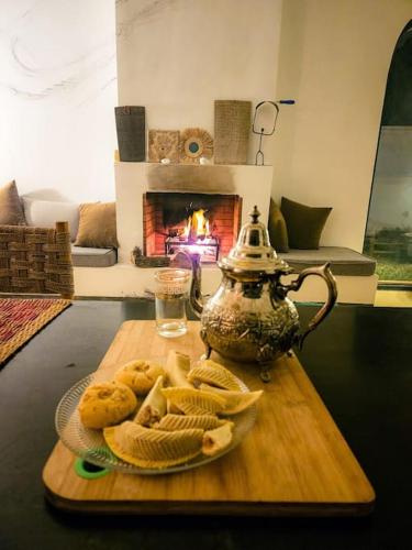 a tea kettle and cookies on a table with a fireplace at Très belle villa avec piscine et vue incroyable sur mediterannée (DAR NAIM) in Tangier