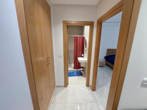 einen Flur, der zu einem Bad mit einem Waschbecken und einem Spiegel führt in der Unterkunft حي الواحات in Tunis