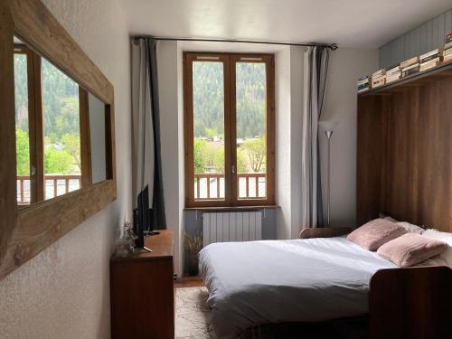 een slaapkamer met een bed en 2 ramen bij Abeille de Chamonix in Chamonix-Mont-Blanc