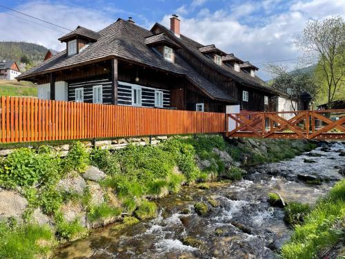 una casa de madera con un puente sobre un río en Chaloupka Kunčice, en Ciudad Vieja de Praga