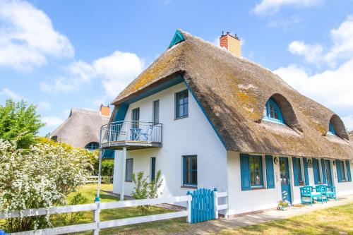 a thatched cottage with a porch and a balcony at Haus Hansi in Wieck