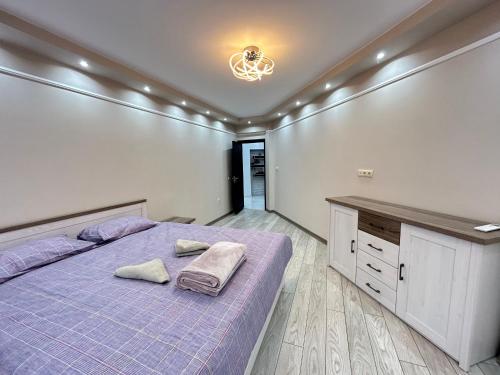 a bedroom with a purple bed with towels on it at Apartament deluxe Karina-Free parking in Burgas City