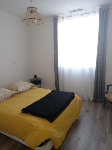 Un dormitorio con una gran cama amarilla y una ventana en Mérignac, en Mérignac