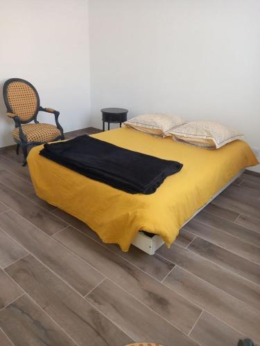 Una cama con una manta amarilla encima. en Mérignac, en Mérignac