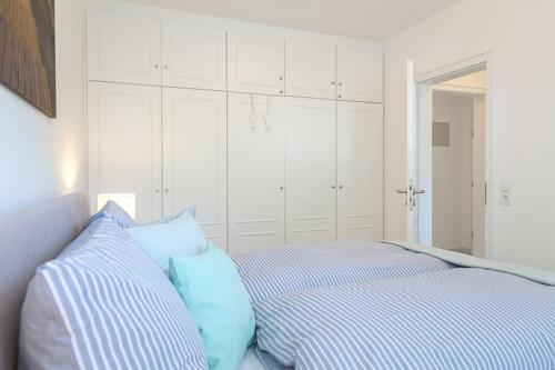 a white bedroom with a bed with blue pillows at Drr20 1 Walter in Westerland