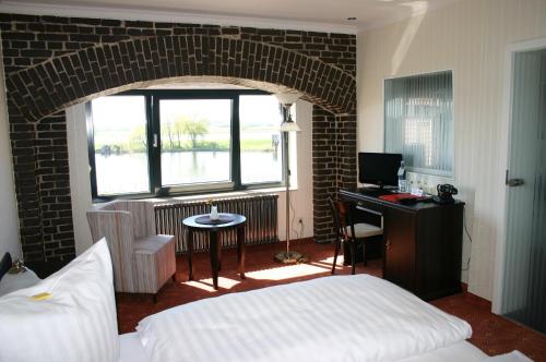 a bedroom with a bed and a desk and a window at Elbe Resort Alte Ölmühle in Wittenberge