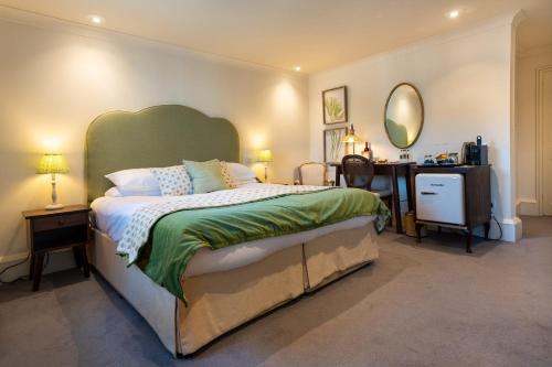 a bedroom with a bed and a desk and a mirror at The Hoste and The Vine House Hotels in Burnham Market