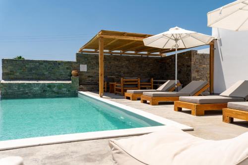 a swimming pool with chairs and an umbrella at Cycladic Breeze Villas in Kampos Paros
