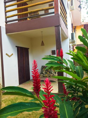 a house with red flowers in front of a building at Pousada das Estrelas in Itaúnas