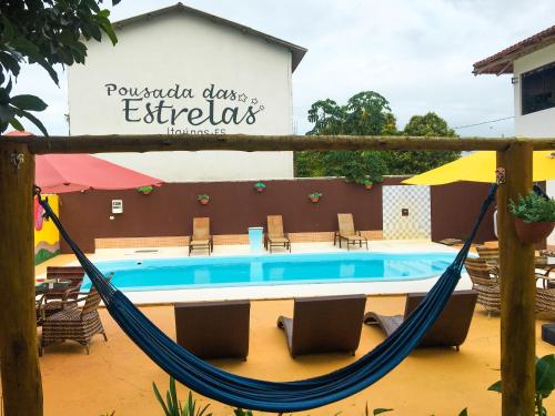 a hammock in front of a swimming pool at Pousada das Estrelas in Itaúnas