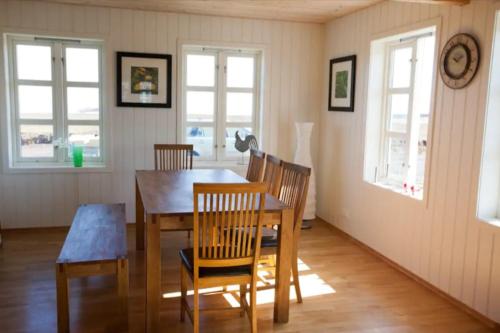 a dining room with a table and chairs and windows at Day Dream Hellnar in Snæfellsbær
