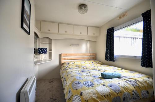 a bedroom with a bed with a yellow and blue comforter at Ideal rural location for beaches, hills and town in Bow Street