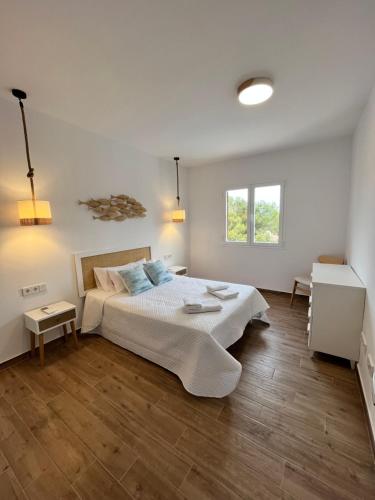 a white bedroom with a bed and a window at Apartamento en Costamar I, 2ª Planta, 23 in Es Pujols