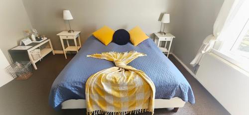 a bed with a blue comforter and yellow pillows at Árból Guesthouse in Húsavík