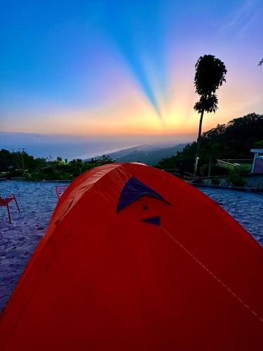 a red tent on the beach with a rainbow in the sky at Glamping Omah Kayu at Watu Paris Jogja in Girijati