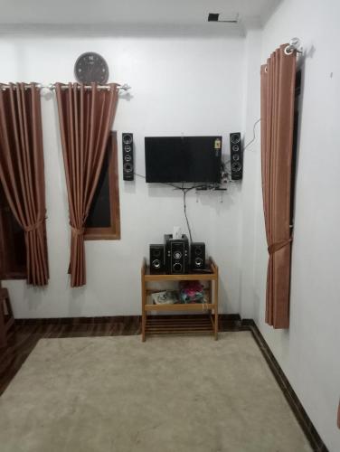 a living room with a flat screen tv and curtains at Homestay putih alenda in Ciwidey