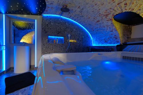 Secret Jacuzzi Mons - Parking privé gratuit في مون: حمام مع حوض استحمام مع إضاءة زرقاء