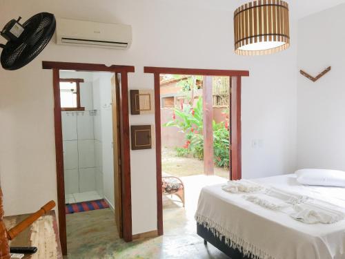 a bedroom with a bed and a glass door to a yard at Pousada das Estrelas in Itaúnas