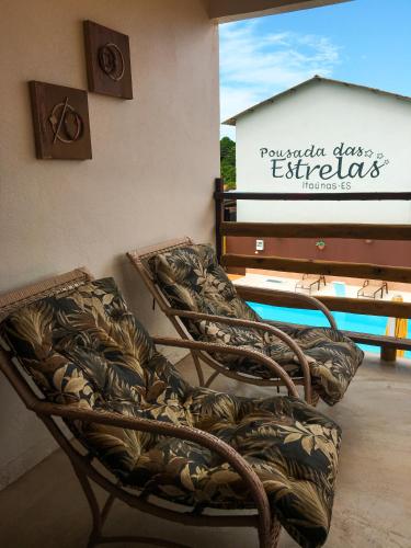 a pair of chairs sitting on a porch with a pool at Pousada das Estrelas in Itaúnas