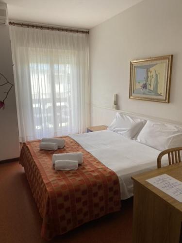 1 dormitorio con 1 cama con 2 toallas en Hotel Rosapineta - Adults Only, en Lignano Sabbiadoro
