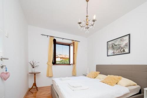 a white bedroom with a bed and a window at Sugar house in Pag