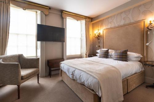 a bedroom with a large bed and a chair at The Hoste and The Vine House Hotels in Burnham Market
