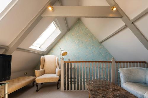 a attic room with a crib and a window at The Hoste and The Vine House Hotels in Burnham Market
