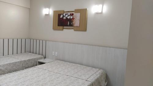 a room with two beds and a picture on the wall at APARTAMENTO SPAZZIO DI ROMA com acesso ao ACQUA PARK SPLASH in Caldas Novas