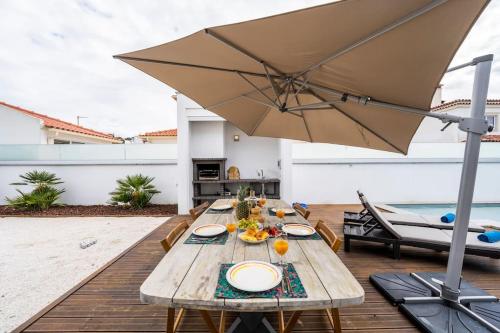 a wooden table with an umbrella on a deck at Villa Nazaré - Pool, BBQ and Boule/Petanque in Nazaré