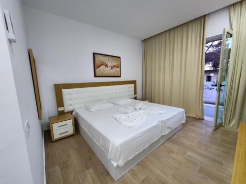 a bedroom with a white bed and a window at Sea Front Villa in Vlorë