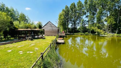 a river with a building next to a house at Chalet avec terrasse sur pilotis vue sur l'étang in Rue